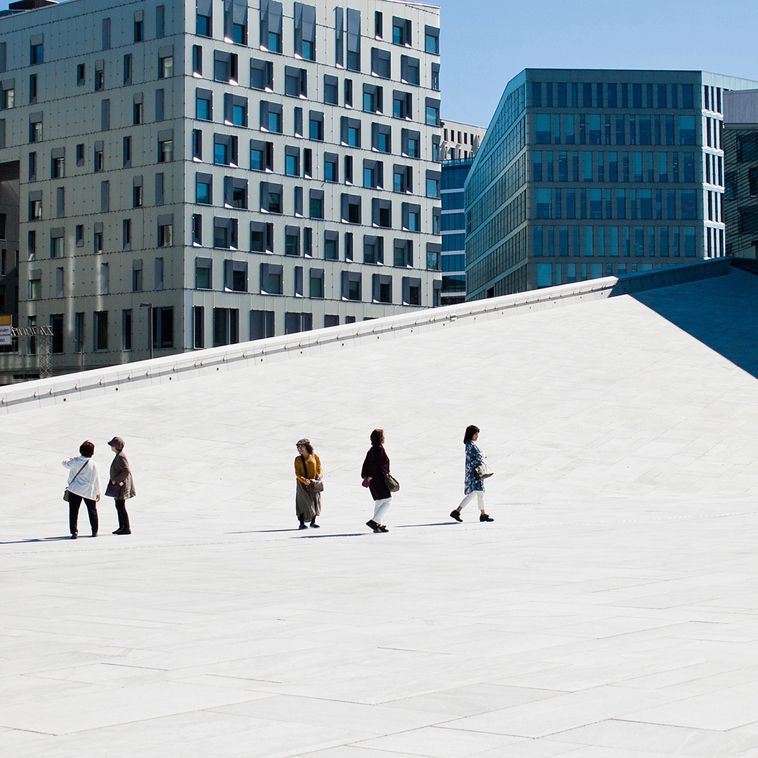 Five tourists walking on the Oslo Opera house on a sunny day. 